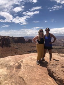 Two women standing on a desert rock formation.