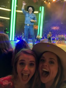 Two women, wide eyes and big smiles, near stage with Garth Brooks singing.