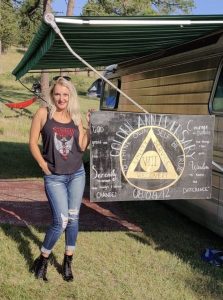 Woman standing next to sign bearing symbol of AA.
