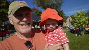 Man holding child, both wearing hats, on a sunny day outside at the Walk for Recovery