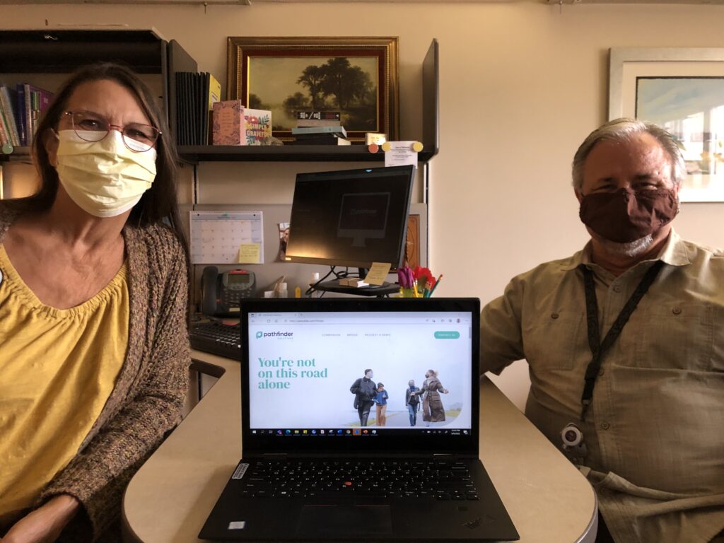 Two counselors sitting next to a laptop.